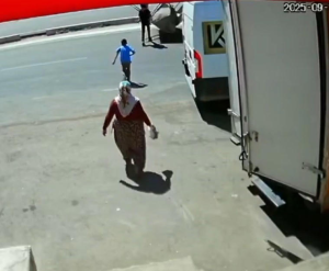 لقطة من كاميرا مراقبة في كهرمان مرعش تظهر لحظة اقتراب طفلين من عبور الطريق قبل وقوع حادث اصطدام بجرافة، بينما تسير امرأة في المقدمة.